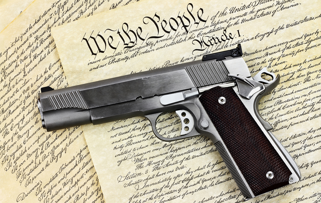 image of a fire arm laying on a copy of the constitution